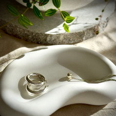 Earrings and necklace with a ball pendant on a white concrete puddle dish with a natural background